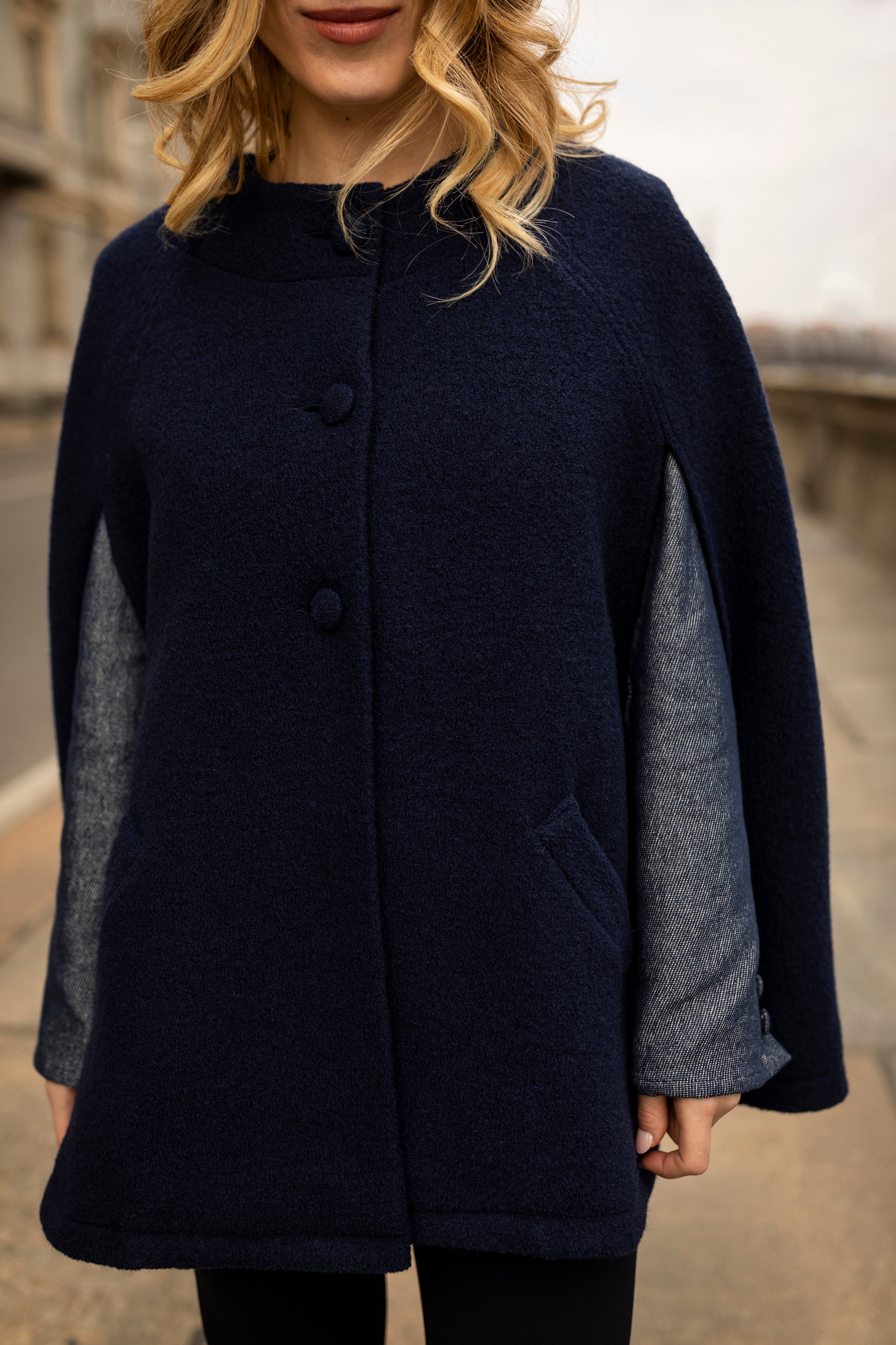 A blonde young girl who wears a blue navy cape by Marta Scarampi
