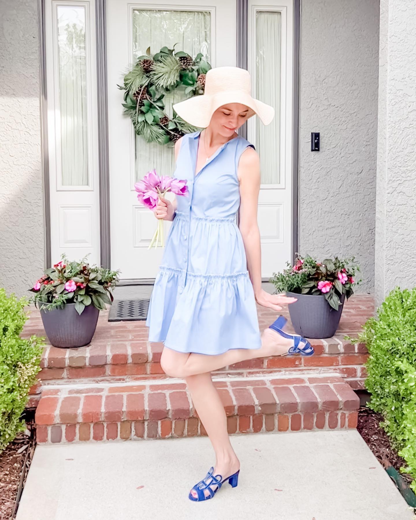 A woman on the doorstep smiles in a Marta Scarampi dress perfect for summer