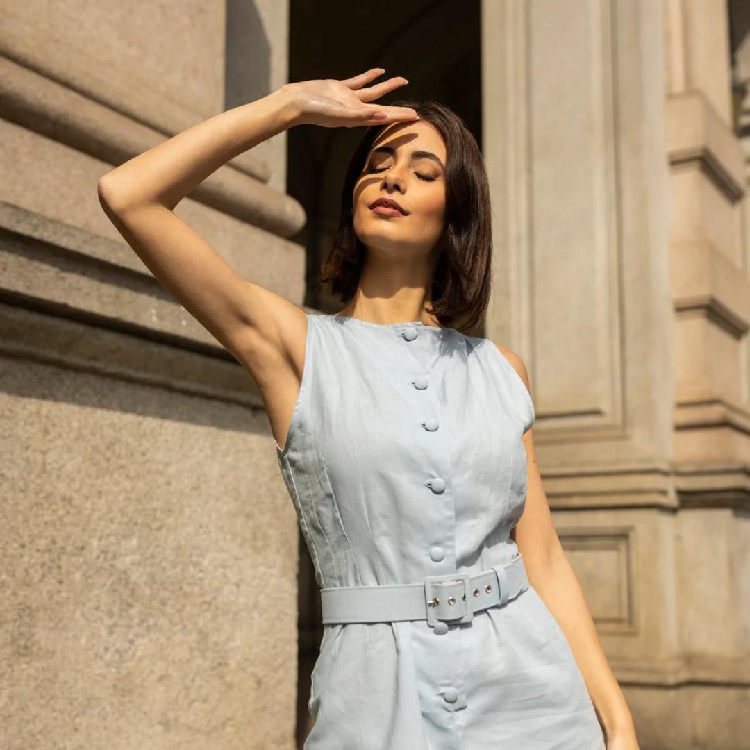 A plain brunette woman raises her arm to protect herself from the sun and wears The Mary Romper dress model born from the collaboration between Marta Scarampi and Mary Hafner